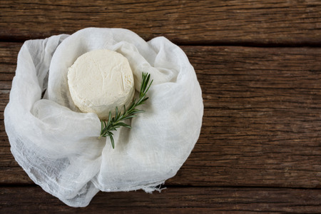 Close-up of cottage cheese and rosemary herb in white cloth on wooden boardの写真素材