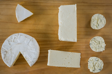 Different types of cheese on wooden board against grey backgroundの写真素材