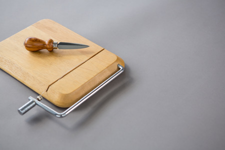 Cheese cutting board with cheese knife against grey backgroundの写真素材