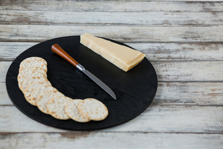 Cheese with biscuits on chopping board against white backgroundの写真素材