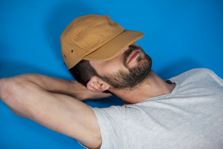 Close-up of man in cap relaxing on blue backgroundの写真素材