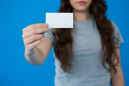 Woman holding a small blank placard against blue backgroundの写真素材