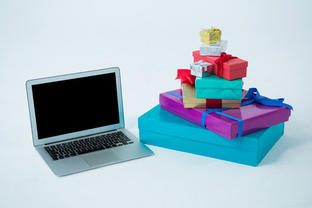 Stack of gift boxes with laptop on white backgroundの写真素材