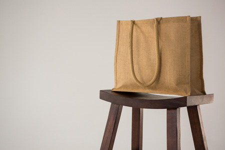Jute bag on wooden stool against white backgroundの写真素材