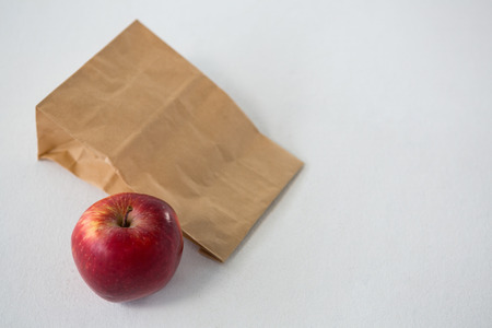 Brown paper parcel bag with red apple against white backgroundの写真素材