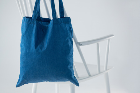 Blue bag hanging on a white chair against white backgroundの写真素材