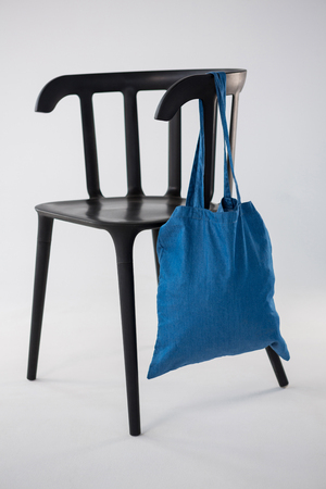 Blue bag hanging on a black chair against white backgroundの写真素材