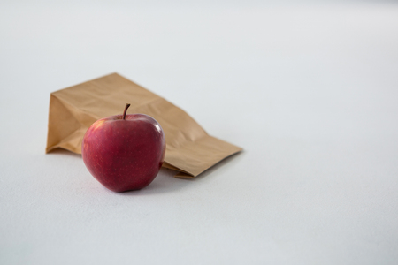 Brown paper parcel bag with red apple against white backgroundの写真素材