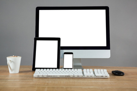 Coffee, desktop pc, digital tablet and smartphone on table in officeの写真素材