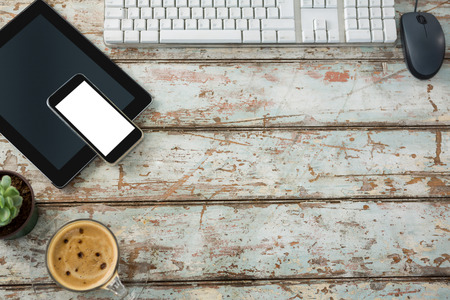 Computer keyboard, mouse, digital tablet and smartphone with coffee cup on wooden tableの写真素材