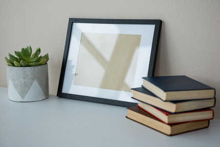 Books with picture frame and pot plant on office tableの写真素材