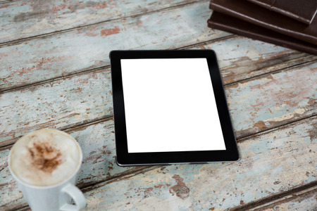 Digital tablet with cup of coffee on table