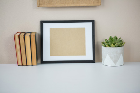Books with picture frame and pot plant on tableの写真素材
