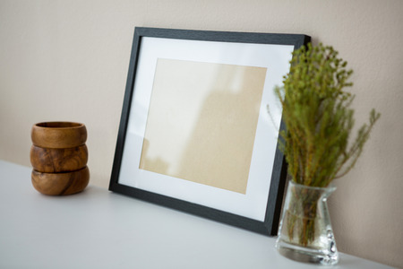 Picture frame with wooden pencil holder and vase on tableの写真素材