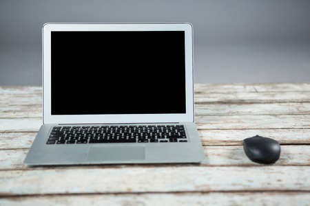 Close-up of laptop and mouse on wooden tableの写真素材