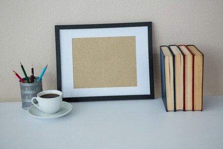 Books with picture frame and a cup of coffee on office tableの写真素材