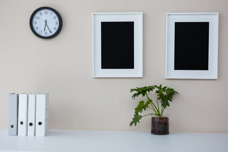 Picture frames and clock on wall in officeの写真素材