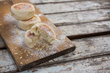 Buns with wheat flour on wooden plank against wooden surfaceの写真素材