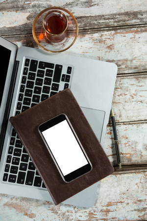 Laptop, smartphone and diary with coffee cup on tableの写真素材