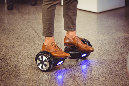 Business executive standing on hoverboard in officeの写真素材