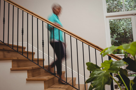 Senior woman walking down stairs at homeの写真素材