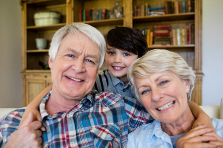Portrait of smiling grandparents with grandson at homeの写真素材