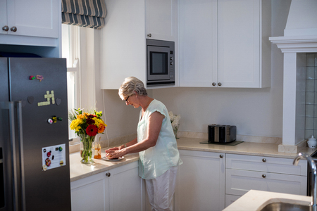 Senior woman preparing breakfast in kitchen at homeの写真素材