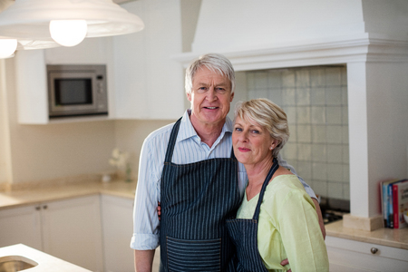 Portrait of senior couple standing in kitchenの写真素材