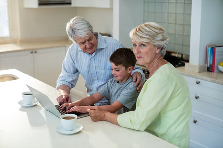 Grandson using laptop with grandparents at homeの写真素材