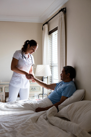 Female doctor examining senior patient in bedroom at homeの写真素材