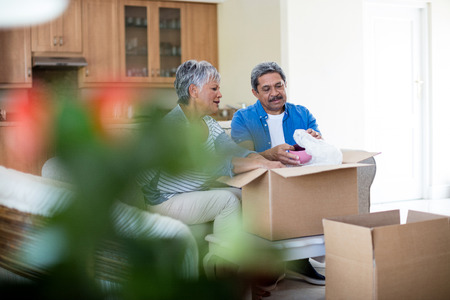 Senior couple unpackaging cardboard box in living room at homeの写真素材