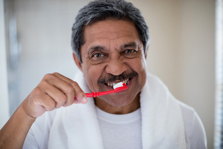 Portrait of senior man brushing teeth in bathroom at homeの写真素材