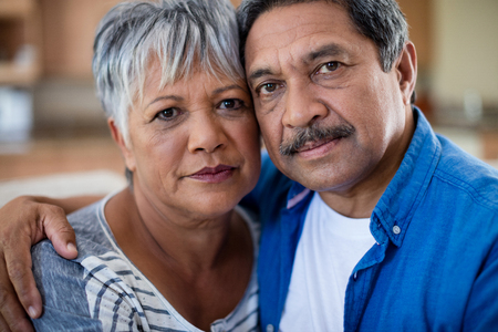 Portrait of senior couple embracing each other in living room at homeの写真素材