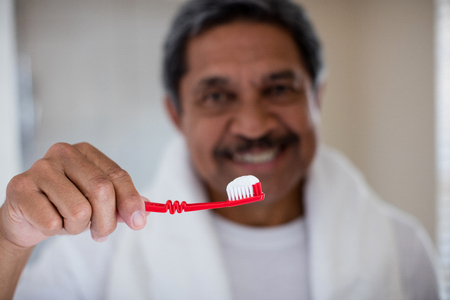 Senior man holding a toothbrush in bathroom at homeの写真素材