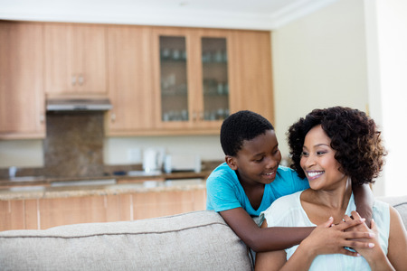 Mother and son embracing each other in living room at homeの写真素材
