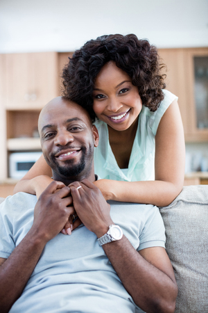 Portrait of smiling couple embracing each other in living room at homeの写真素材