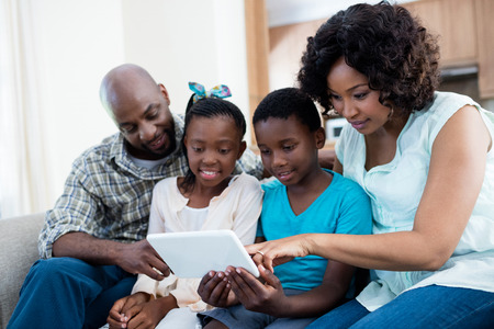 Parents and their children using digital tablet in living room at homeの写真素材