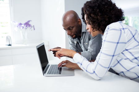 Couple using laptop in living room at homeの写真素材