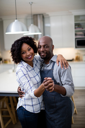 Portrait of romantic couple dancing in kitchen at homeの写真素材