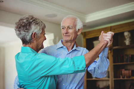 Senior couple dancing together in living room at home