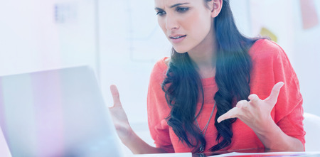 Annoyed designer gesturing in front of her laptop in her officeの写真素材