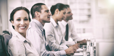 Businesswoman in bright office smiling at camera while her colleagues listening to presentationの写真素材