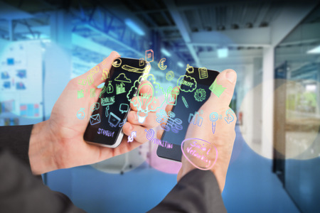 Businessman holding a phone in each hand against illuminated lightの写真素材