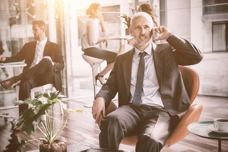 Businessman talking on mobile phone while sitting on chair in office