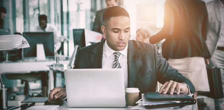 Focused businessman working on laptop at desk in office