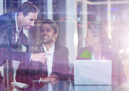 Stocks and shares against businesswoman discussing with colleagues over laptopの写真素材