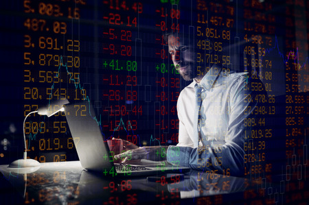 Stocks and shares against businessman using laptop at night