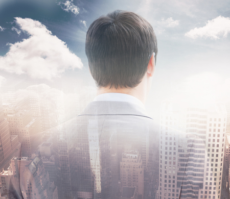 Rear view of businessman looking through window of building  against aerial view of a city on a cloudy day 3dの写真素材