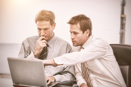Two handsome businessmen working together on a project sitting at a table in the office