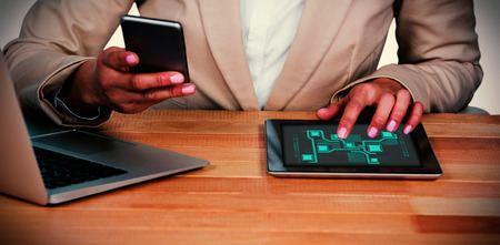 Technology interface  against midsection of businesswoman using mobile phone and digital tablet with laptop on tableの写真素材